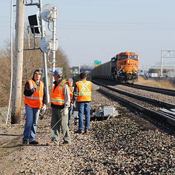 A BNSF locomotive pulls a train in a students watch from along the tracks.